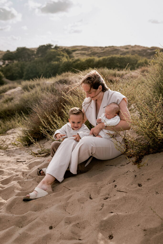 Een mama met haar baby en peuter tijdens een gezinsfotoshoot die voelt als een fijn uitje in de duinen van Noordwijk.