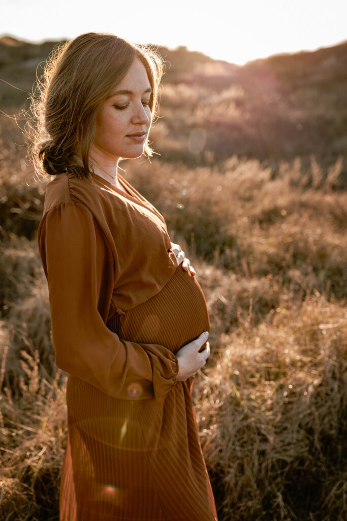 Zwangere mama-to-be tijdens een fotoshoot in de duinen van Noordwijk op een ongedwongen manier.